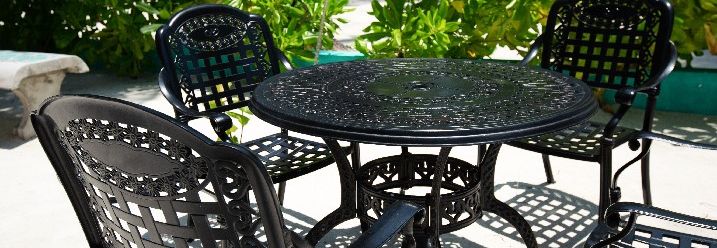 Schwarze Gartenstühle mit Tisch aus Metall auf Terrasse.